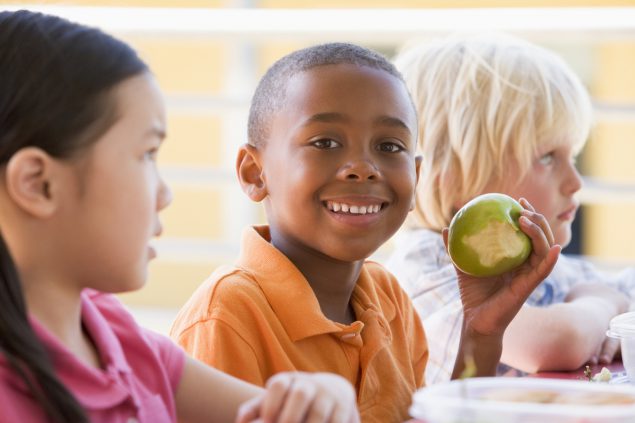 African American child eating apple at school.