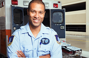 Male EMT standing next to ambulance.