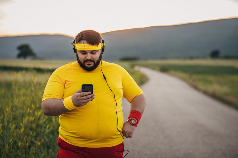 Overweight man using smart phone on break from training
