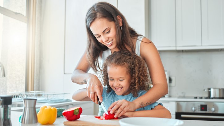 Mother and daughter cutting vegetables at the kitchen counter.