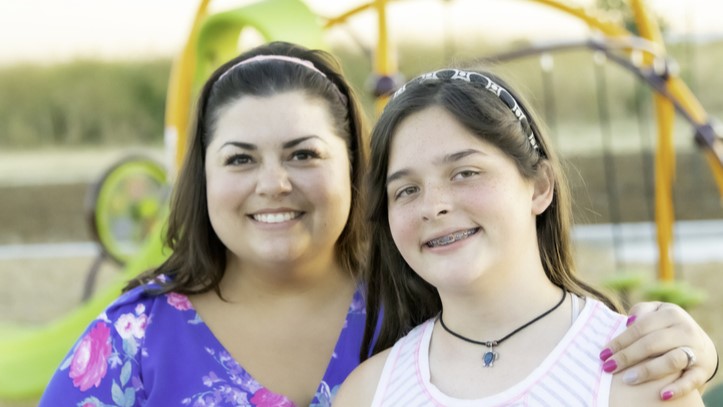 Mother and daughter at a playground smiling.