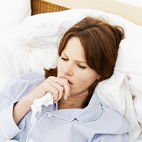 woman in bed coughing