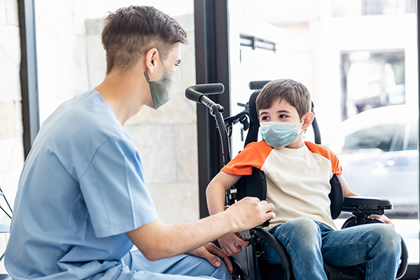 Child in wheelchair talking to HCP