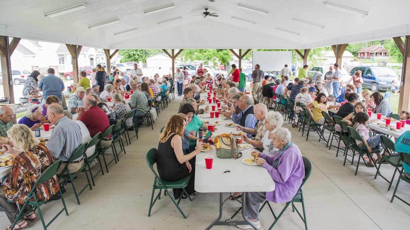 A congregation eating at table at a church potluck.