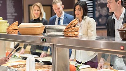 Four young adults in cafeteria serving line.