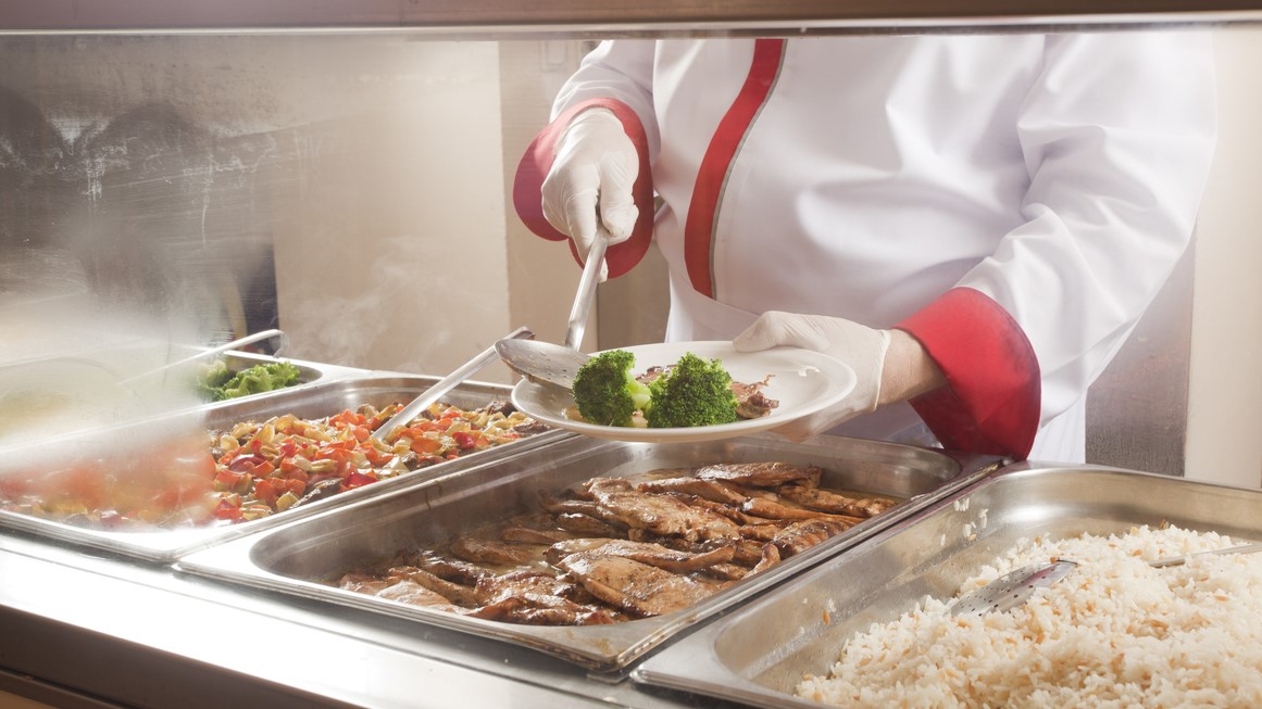 Server dishing up a meal in a food service line.