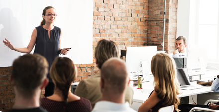 Photo of a woman training a room full of people.