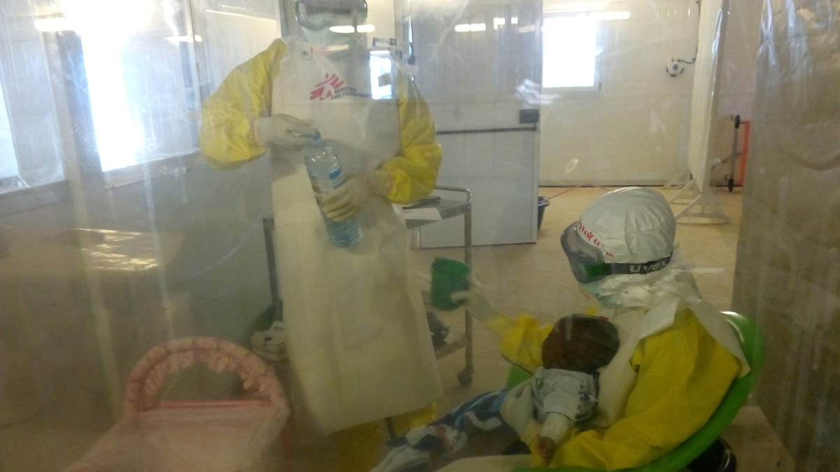 two people in protective gear treating a baby in quarantine