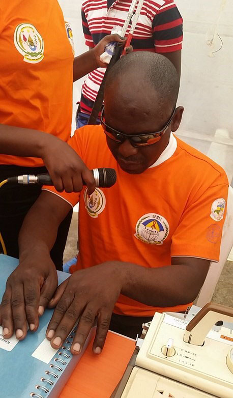 A man reads out HIV/AIDS information written in Braille. (Photo Courtesy of UPHLS)