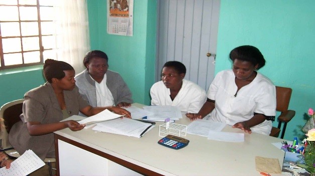 FHI Surveillance Officer, seconded at TRAC, Dr. Eugenie Kayirangwa reviewing surveillance materials with ANC providers at a health center in Rwanda.