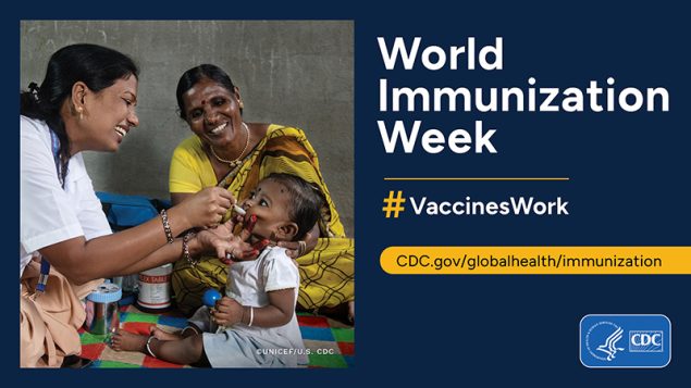 Two health workers giving a vaccine to a child