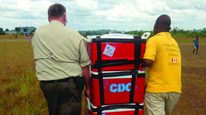 Mike Staley (CDC) and Alie Brima Tia (Sierra Leone Ministry of Health), transporting Ebola specimens from a UN helicopter, to the CDC Bo Lab in Sierra Leone, 2015.   Credit: Tara Sealy