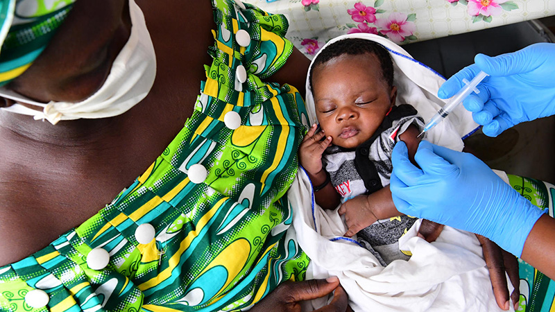 A baby is weighed and vaccinated in the health center of Gonzagueville, a suburb of Abidjan, in the Côte d'Ivoire. His mother and the nurses wear masks and gloves to protect against the COVID-19, 2020.