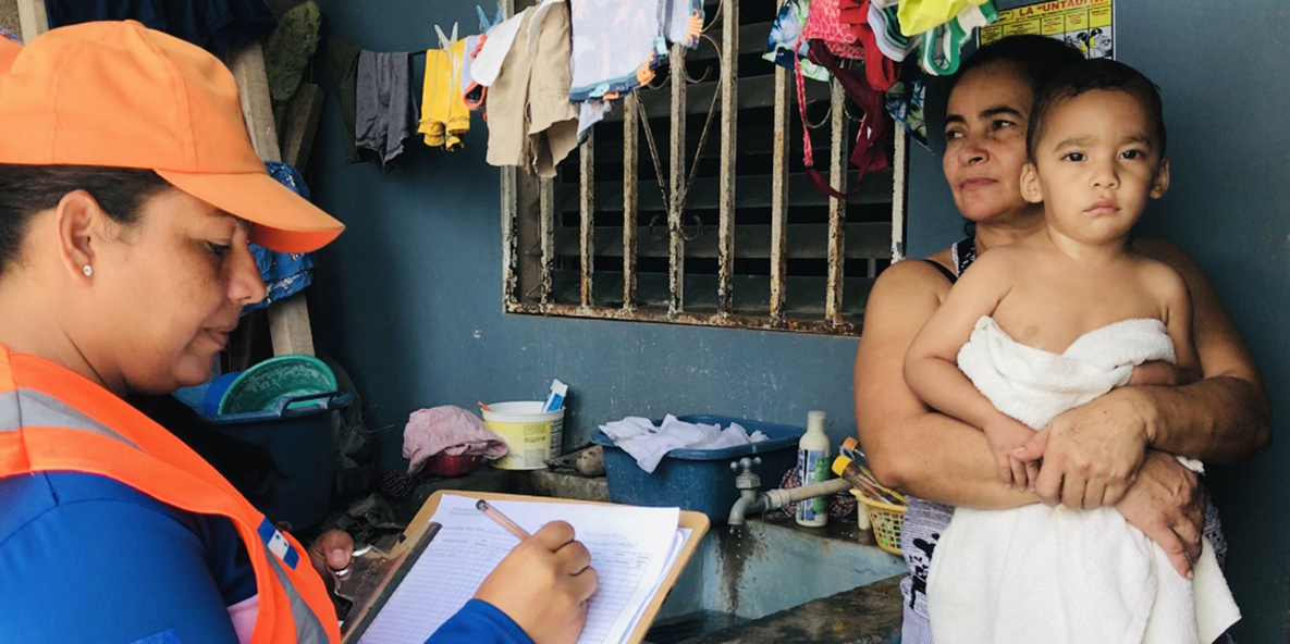 Local community volunteer collects information from a mother about dengue control practices and provides suggestions for protecting her family. Photo credit: Jahn Jaramillo