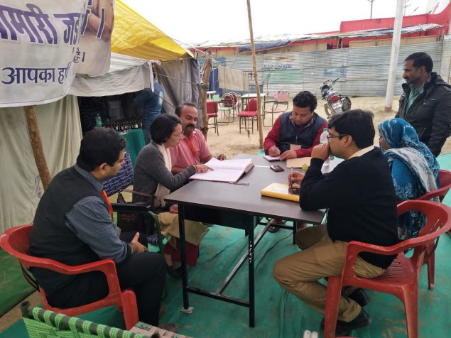 (India EIS officers from NCDC are reviewing the out-patient register formats at a field unit while planning the daily disease surveillance at Kumbh mela.   Photo credit: Dr. Rajesh Yadav)