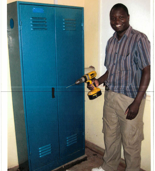 Lucius holds a drill while installing a server cabinet at a remote health facility in Malawi.