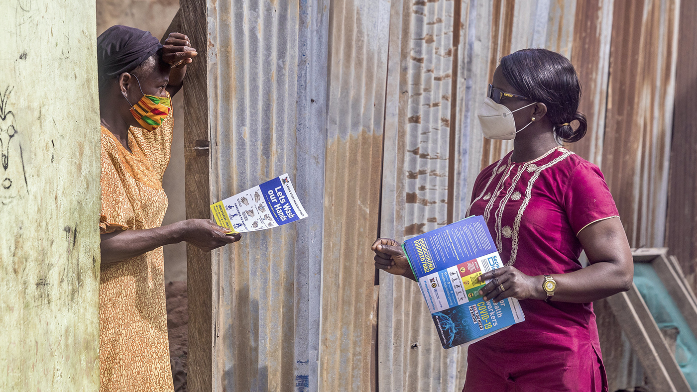 A volunteer hands out handbills as part of campaign to raise awareness about COVID-19