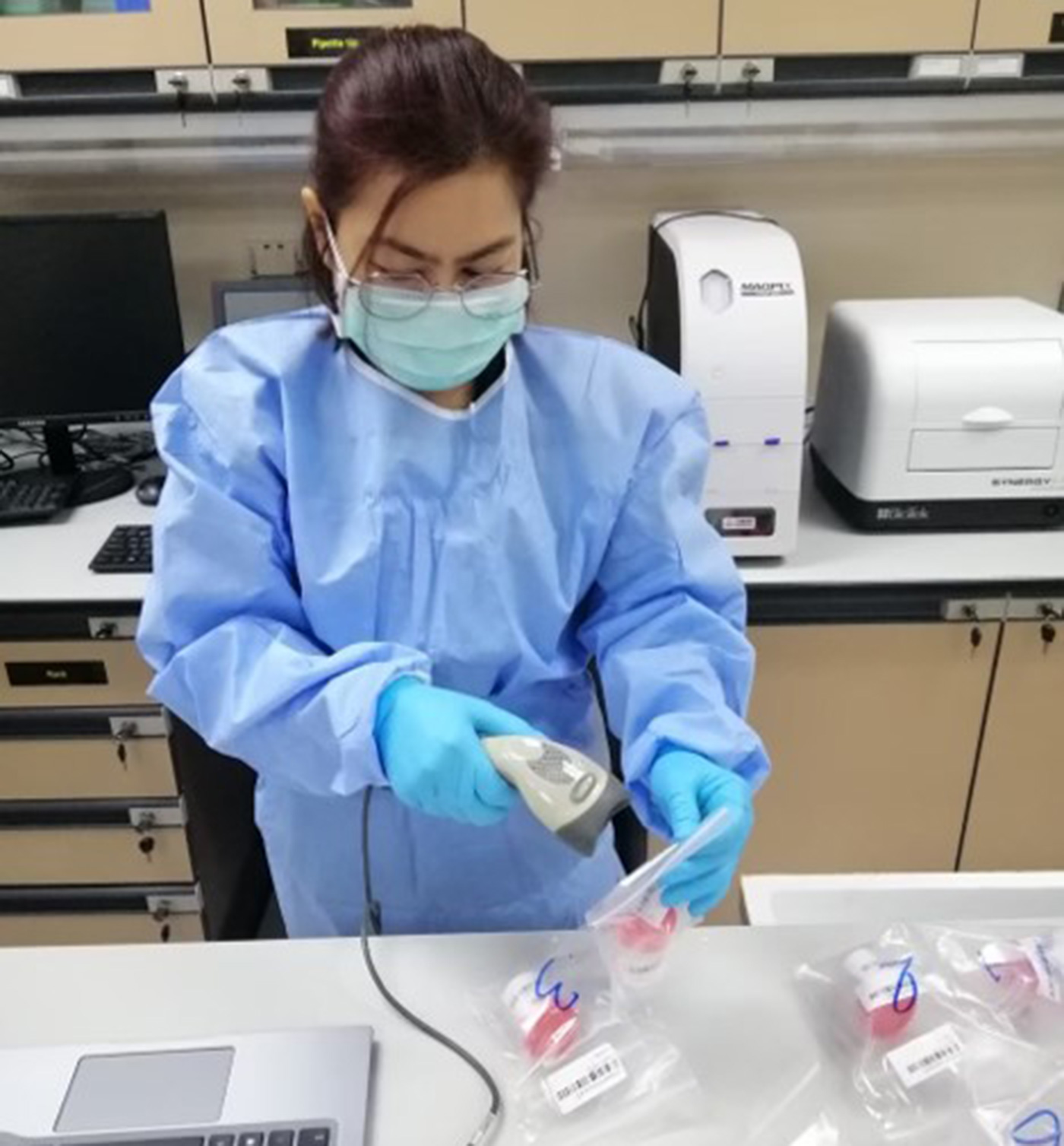 A lab technician uses a bar code reader to directly transfer patient information to the receiving database