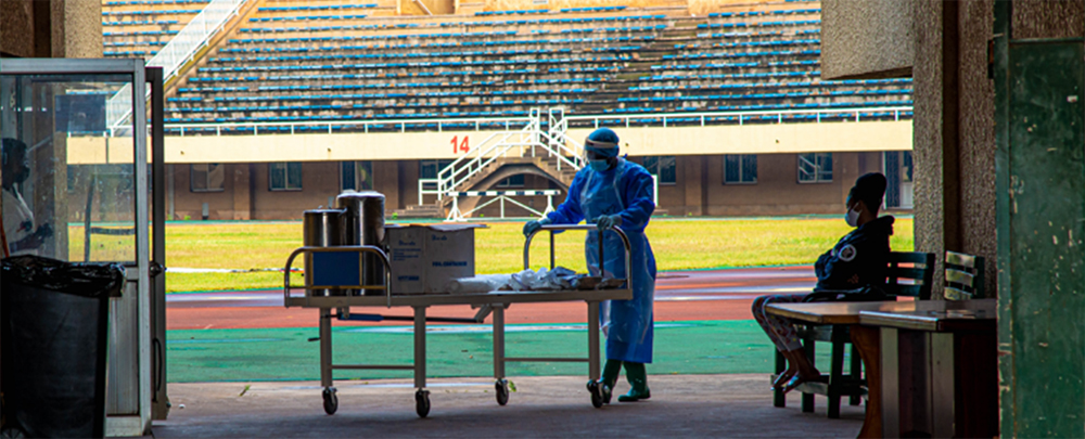 A healthcare worker takes supplies to the COVID-19 treatment facility inside Namboole soccer stadium.