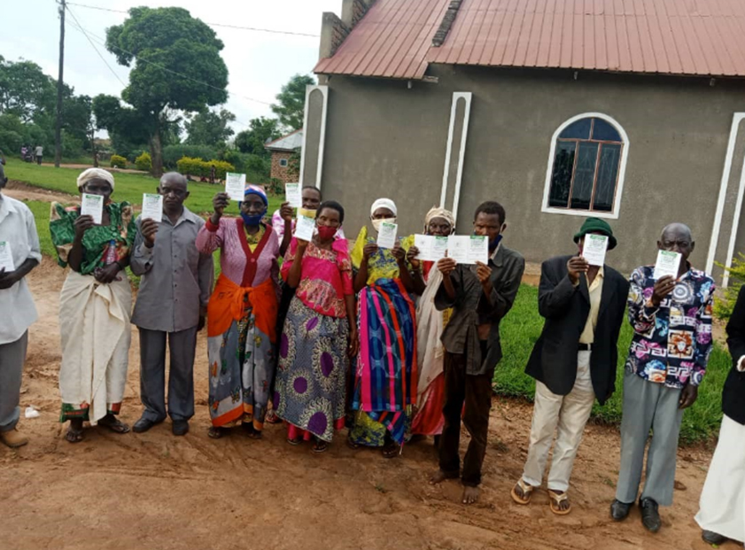 A group of people aged 70 years and  older hold up their vaccination cards