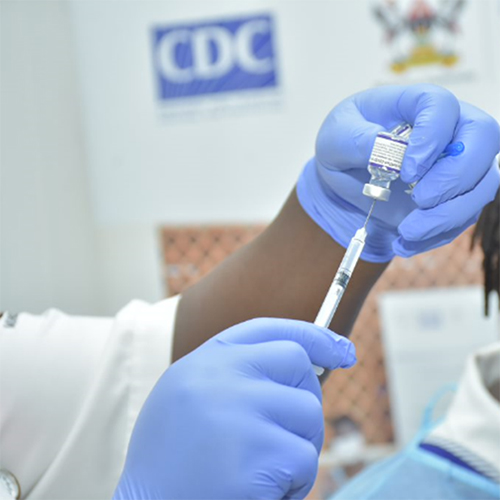 A health worker draws a dose of COVID-19 vaccine from a small bottle during a mass vaccination