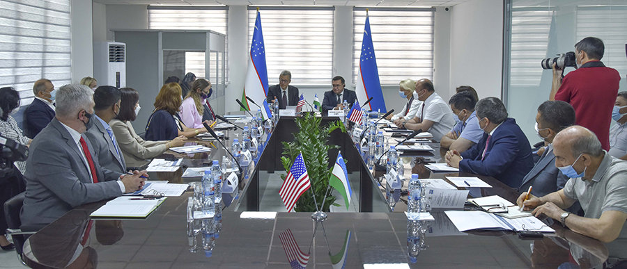 Conference room of people with the flags of the Republic of Uzbekistan and the United States of America