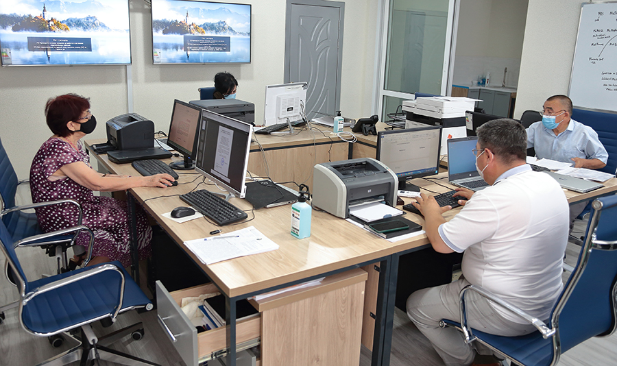 Four individual sitting at work stations around adjoined desks