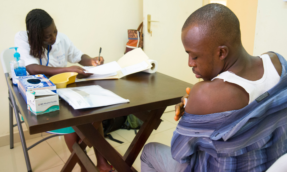 After receiving the vaccine, Benjamin Kamara waits while Nurse Rashidatu Bundu fills out paperwork for the study.  Prior to joining the STRIVE team, Ms. Bundu worked in in a government hospital in Kenema, a district in Sierra Leone that was heavily affected by Ebola.