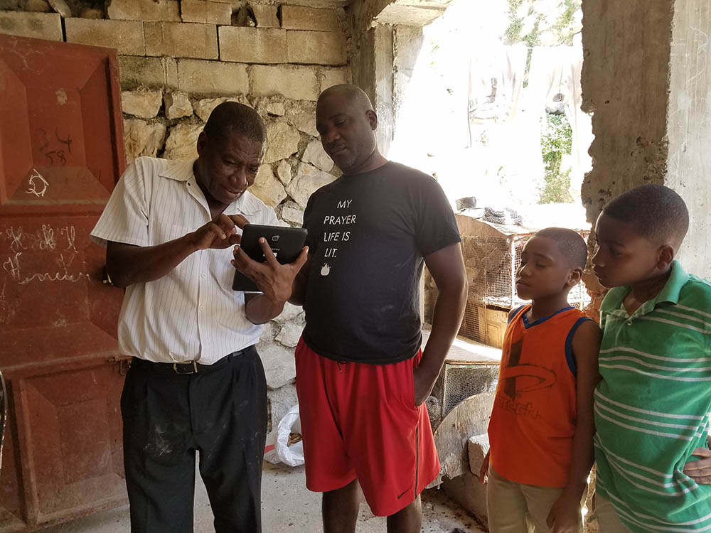From the Haiti pilot. The vector surveillance technician (L. Balthazar, holding the tablet) using the app to collect demographic information from the head of the household. Once community members saw how he entered their information into the app, they were eager to participate and volunteer their households for vector surveillance.