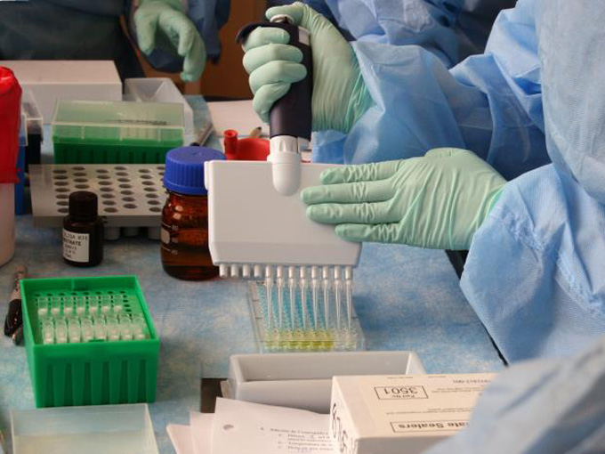 a lab worker in protective clothing adding a solution to an ELISA plate