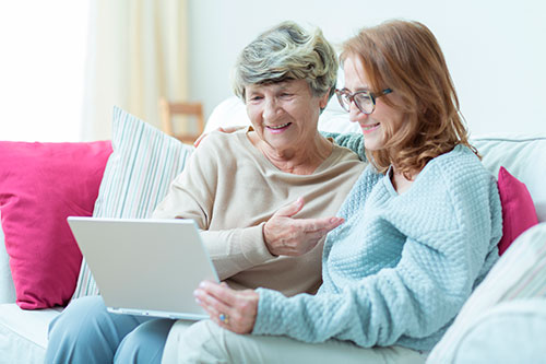 An older woman reading on a laptop with her daughter