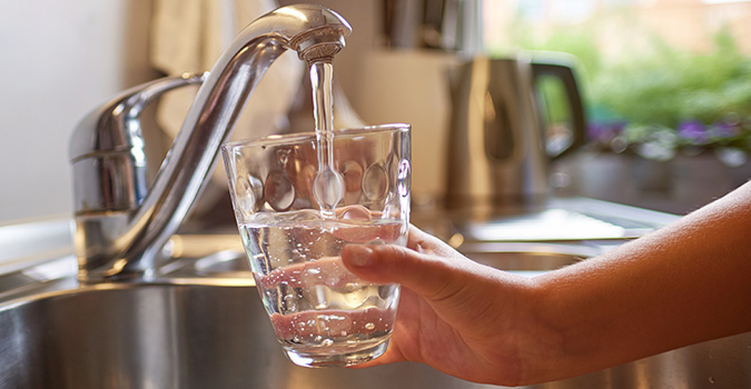 A person pouring water into a cup.