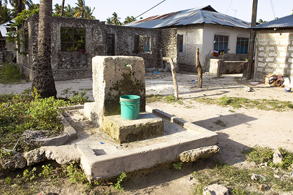 Drinking water supply, well in african village. Plastic container under the tap. Problem with access to the water in africa.