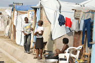 People in front of their homes in a refugee camp.