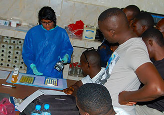 Environmental microbiologist Gouthami Rao holds a black light over a  water sample to see if it will glow, indicating contamination