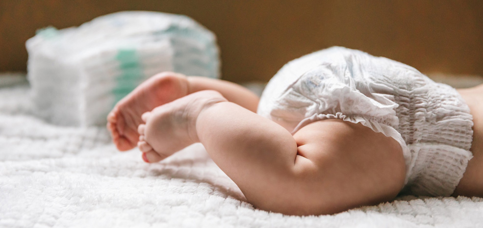 A baby in a diaper and a stack of diapers