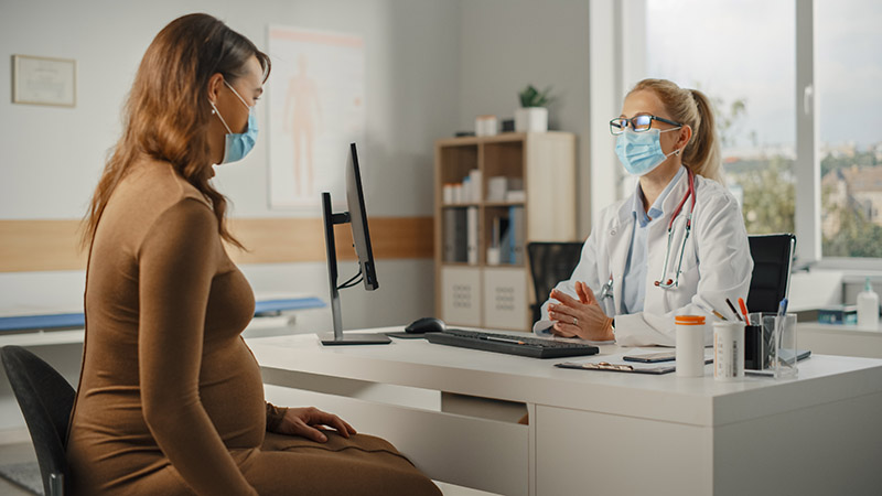 Female Family Doctor is Talking with Young Pregnant Patient During Consultation in a Health Clinic.