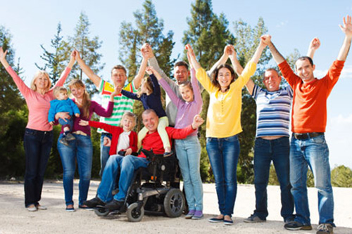 Photo of disabled man in a wheelchair outside with his family