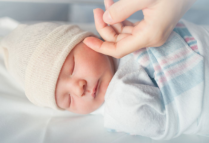 Mom touching baby's face while baby is sleeping