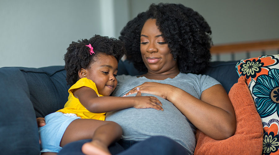 A pregnant mother holding her daughter