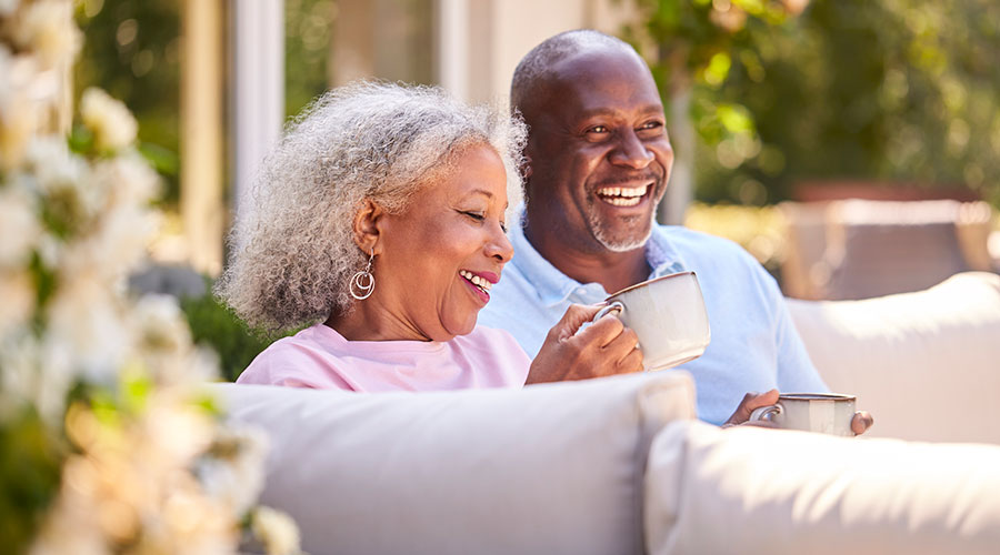 Happy senior couple sitting outside on a couch