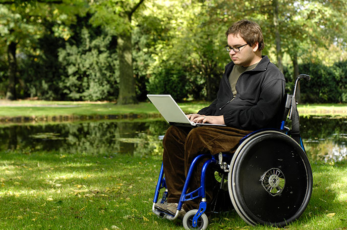 Young man in a wheelchair using a laptop computer