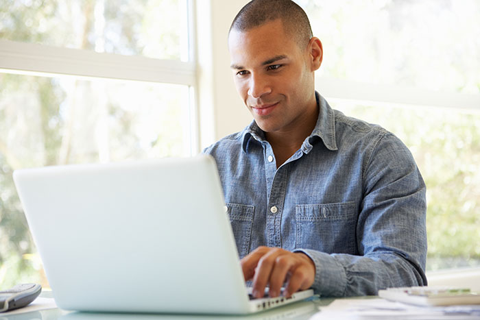 Young man sitting at a table using a laptop