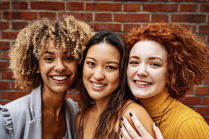 Three multi-ethnic women posing for picture