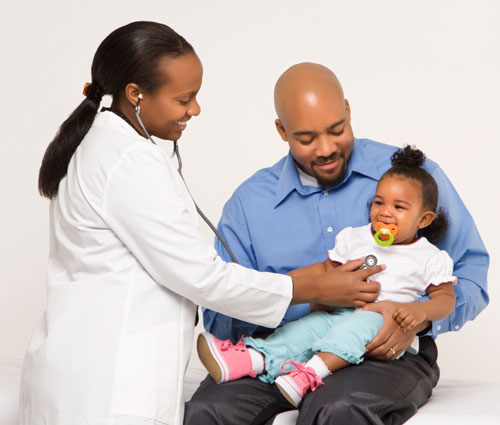 A father holding his daughter at her doctor visit