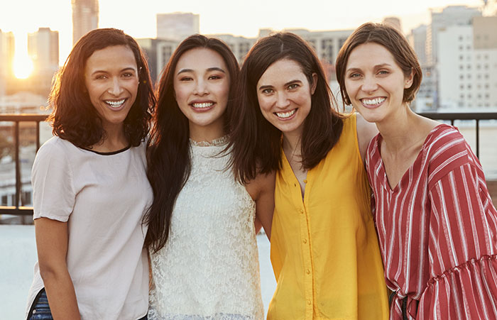 Women posing for a picture with the skyline behind them.