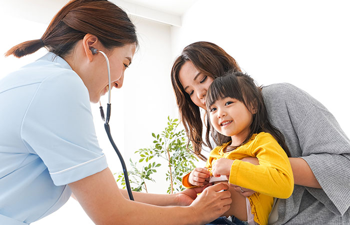 A mother holding her daughter during a doctor examination