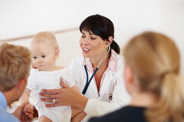 Doctor handing a baby to his parents.