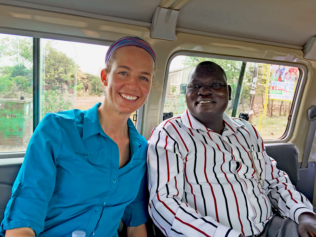 A woman and a man smile into the camera sitting in a bus.