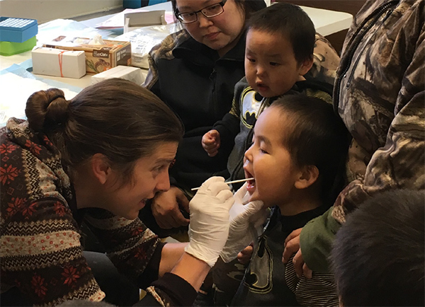 A woman swabbing the inside of a young boy's mouth